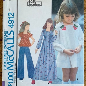 May include: A vintage sewing pattern for children's and girls' dresses or tops. The pattern is from McCall's and is number 4912. The pattern includes three different styles: a long-sleeved dress with a floral print, a short-sleeved top with a floral print, and a white dress with cherry embroidery. The pattern is labeled "easy to sew".