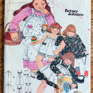 May include: Vintage Butterick sewing pattern, size 3, featuring illustrations of young girls in dresses and a baby carriage. The pattern cover includes the text "Butterick" and "Betsey Johnson".