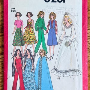 May include: A Simplicity 8281 sewing pattern envelope with a bright pink border. The front displays illustrations of seven different outfits for dolls, including a wedding gown with a veil, a blue cape, floral dresses, a jumpsuit, and pantsuits.