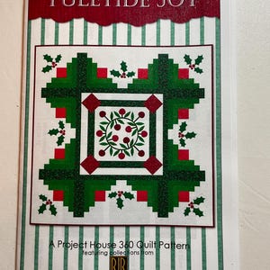 Könnte beinhalten: Ein Quiltmuster mit dem Titel "Yuletide Joy" mit einem festlichen Design. Das Muster zeigt ein zentrales Quadrat mit einem Kranz aus roten Beeren und grünen Blättern, umgeben von grünen und roten Blöcken. Der Umschlag enthält den Text "A Project House 360 Quilt Pattern".