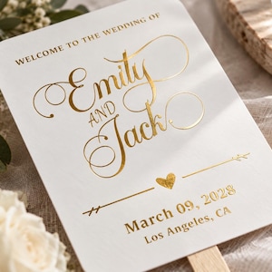 以下が含まれることがあります： 金箔の文字で「WELCOME TO THE WEDDING OF Emily AND Jack」と書かれた白い長方形のウェディングファン。小さな金のハート、矢印のグラフィック、2028年3月9日という日付、そしてロサンゼルス、カリフォルニアという場所が下に印刷されています。