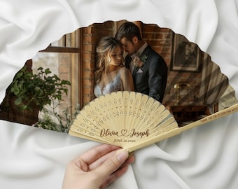 May include: A wooden hand fan with a printed photograph of a couple. The fan is personalized with the names "Olivia & Joseph" and the date "June 12, 2026". The fan also has the text "THANK YOU FOR CELEBRATING WITH US!"