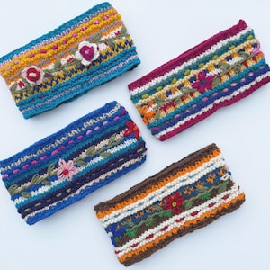 May include: Four colorful knitted headbands with embroidered floral designs. The headbands are made of a soft, textured yarn and feature a variety of colors, including blue, red, orange, yellow, green, and white.