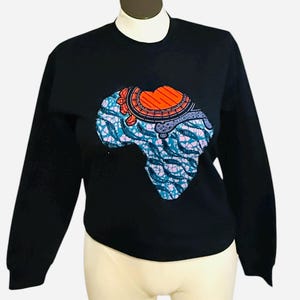 Peut inclure: Sweat-shirt noir orné d'un motif coloré du continent africain. Le motif intègre des motifs bleus, oranges et roses, créant un graphisme vibrant et accrocheur. Le sweat-shirt a des manches longues et un col rond.