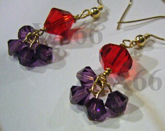 May include: A pair of earrings with red and purple crystal beads. The earrings are made with gold wire and have a dangling design.