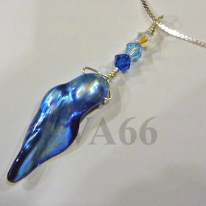 Puede incluir: Un collar de cadena de plata con un colgante de concha iridiscente azul y cuentas de cristal azul y transparente.
