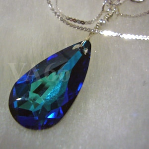 May include: A teardrop-shaped pendant necklace with a large blue and green crystal. The crystal is faceted and reflects light.