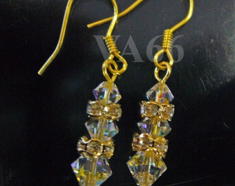 May include: A pair of gold dangle earrings with clear crystal beads. The earrings have a simple design and are perfect for everyday wear.