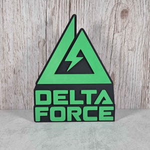 Può includere: Un cartello triangolare verde e nero con un fulmine all'interno del triangolo e il testo "DELTA FORCE" sotto.