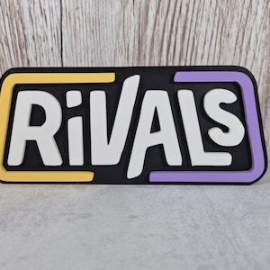 May include: A black sign with the word "RIVALS" in white letters. The sign has a yellow border on the top and a purple border on the bottom.