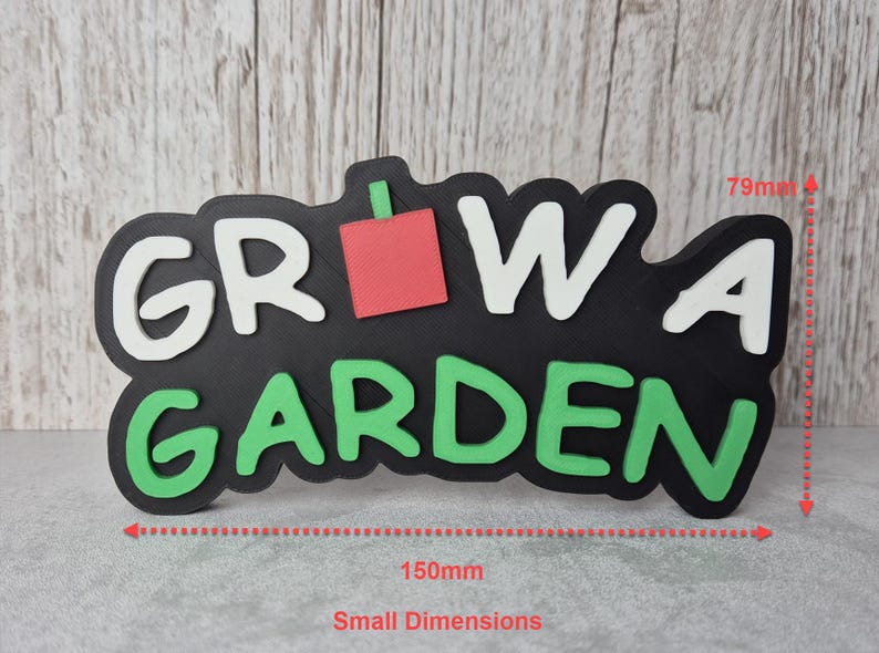 Puede incluir: Un letrero negro con las palabras "GROW A GARDEN" en blanco y verde, con un cuadrado rojo. El letrero mide 15 cm de ancho y 7,9 cm de alto, ideal para la decoraci&oacute;n del jard&iacute;n.