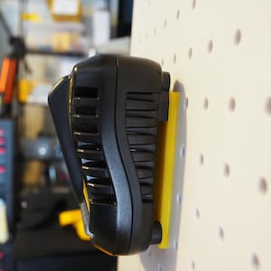 May include: A black and yellow battery charger mounted on a white pegboard wall.