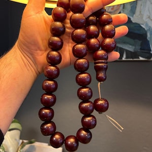 May include: A dark red wooden prayer beads or rosary with a tassel. The beads are round and smooth.