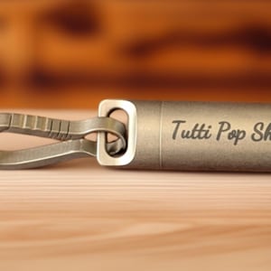 May include: A silver metal keychain with a carabiner clip and a cylindrical tag that says "Tutti Pop Shop".