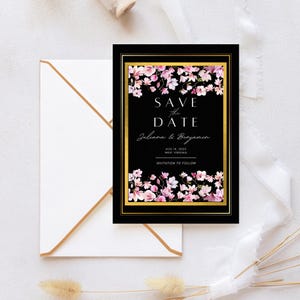 Peut inclure: Carte Save the Date noire avec bordure dorée et motifs floraux. La carte présente le texte « Save the Date » et les noms Juliana & Benjamin, ainsi que la date du 14 août 2023 et le lieu West Virginia. Une enveloppe est incluse.