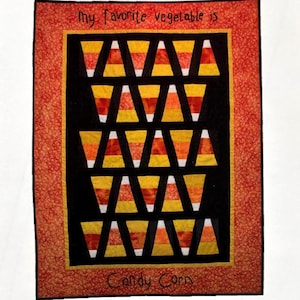 May include: A wall hanging quilt with a black background featuring rows of candy corn in yellow, orange, and white. The quilt is framed with a red and orange border. Text reads "My favorite vegetable is Candy Corn". The quilt measures 31" x 41".