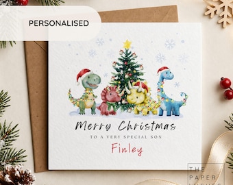 May include: A square Christmas greeting card featuring a watercolor illustration of four dinosaurs wearing Santa hats and wrapped in colorful string lights around a decorated Christmas tree. Text reads Merry Christmas to a very special son Finley.