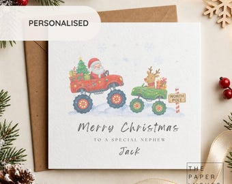 May include: A square white Christmas greeting card featuring a watercolor illustration of Santa Claus driving a red monster truck and a reindeer driving a green monster truck. Text reads: Merry Christmas to a special nephew Jack.