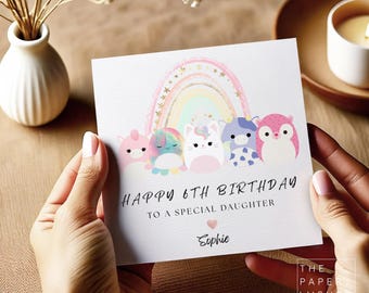 May include: A square birthday card featuring a pastel rainbow with gold stars above five colourful plush-style animal characters. The text reads HAPPY 6TH BIRTHDAY TO A SPECIAL DAUGHTER with a small pink heart and the name Sophie below.