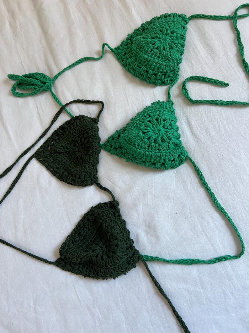 May include: Two crocheted bikini tops, one in a dark green and one in a lighter green. The tops are made with a delicate, intricate stitch pattern.