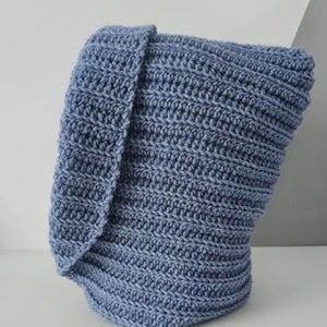 Op de afbeelding: Een blauwe gehaakte sjaal met capuchon. De sjaal is gemaakt met een textuur-steek en heeft een lange, vloeiende capuchon.