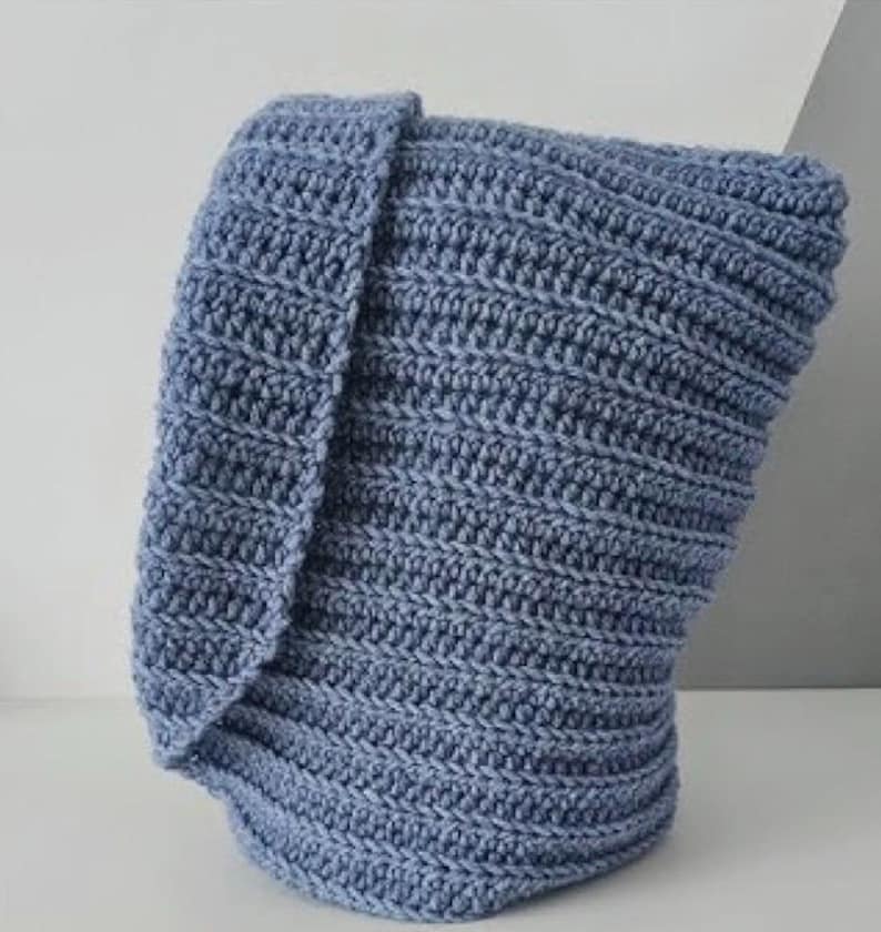Op de afbeelding: Een blauwe gehaakte sjaal met capuchon. De sjaal is gemaakt met een textuur-steek en heeft een lange, vloeiende capuchon.