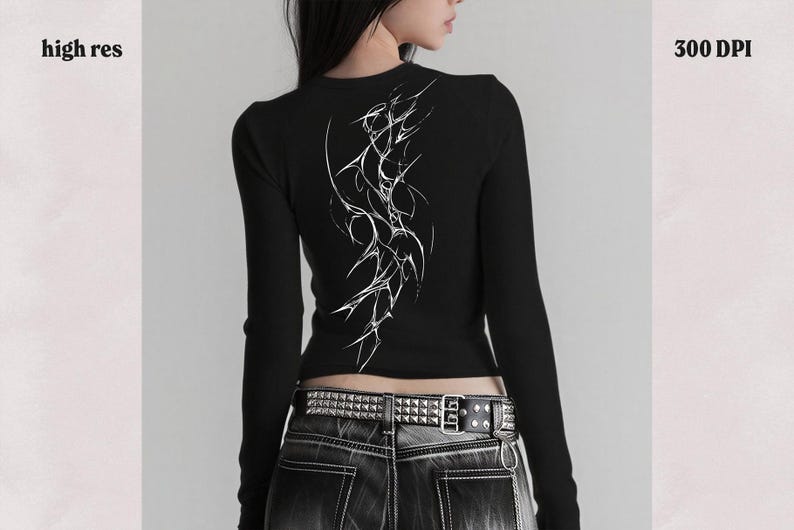 May include: Black long-sleeve top with a white abstract design on the back. The top is ribbed and form-fitting. The model is wearing a studded belt and dark wash jeans. The image also includes the text "high res" and "300 DPI".