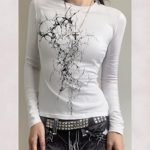 May include: White long-sleeve shirt with a black abstract design. The graphic resembles a network of interconnected lines and shapes. The shirt is paired with a studded belt and dark-colored pants. Text on the image reads "high res" and "300 DPI".
