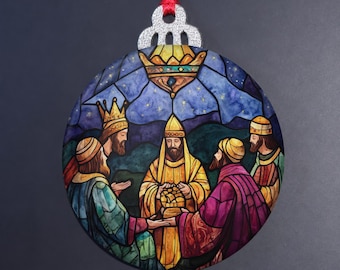 Może przedstawiać: Okrągła, płaska ozdoba świąteczna z ilustracją w stylu witrażu przedstawiającą Trzech Króli składających dary. Postacie ubrane są w szaty w odcieniach niebieskiego, żółtego i fioletowego, z czerwoną wstążką i srebrną, brokatową zawieszką.