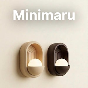 May include: Two wall sconces with the text Minimaru above them. One sconce is beige and the other is dark brown. Each features an oval frame with an arched interior design and a glowing white spherical light bulb resting in a semi-circular base.