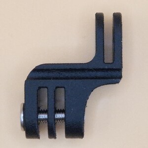 May include: A black metal bracket with a slotted design and a silver screw. The bracket has a right-angle shape with two parallel slots on one end and a single slot on the other. The item is likely a mounting component.