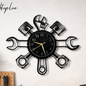 May include: Black wall clock with a mechanic theme. The clock features a round face with gold hands, surrounded by wrench, piston, and connecting rod cutouts. The text "LightupLux" is in the upper left corner.