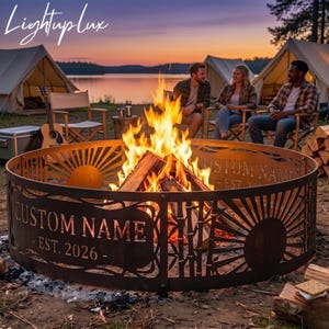 May include: A circular metal fire pit ring featuring laser-cut designs of suns and bamboo stalks. The metal surface includes the text CUSTOM NAME and EST. 2026. A bright orange and yellow fire burns inside the ring, illuminating the dark metal structure.