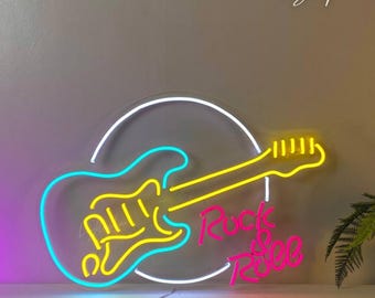 May include: A neon sign featuring a white circular outline, a cyan and yellow electric guitar shape, and the pink neon text "Rock & Roll". The sign is mounted on a wall, displaying vibrant light tubes that form the musical instrument and lettering.