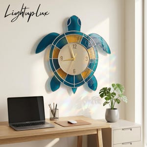 May include: A wall clock shaped like a sea turtle with a stained glass-style shell in shades of teal and amber. The central clock face is gold with black numerals 3, 6, 9, and 12, featuring gold hands. The text LightupLux is visible.