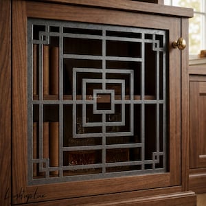 Puede incluir: Una puerta de armario de madera marrón oscuro con una rejilla metálica rectangular central de patrón geométrico. La puerta incluye un pequeño pomo redondo de latón en el lado derecho. A través de la celosía se ven libros y decantadores de cristal.