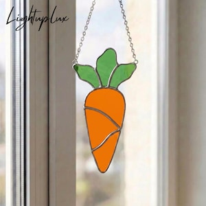 Op de afbeelding: Gebrandschilderde wortel zonnevanger met oranje lichaam en groene bladeren, hangend aan een zilveren ketting. Het wortelontwerp is zilver omlijnd. De tekst "LightupLux" staat in de linkerbovenhoek.