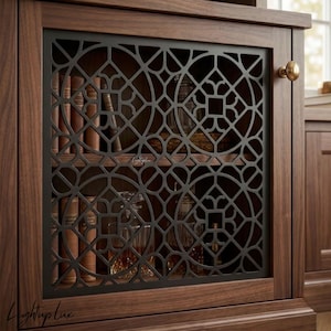 May include: A dark wood cabinet door featuring a black metal grille with a geometric circular pattern. The door has a round brass knob and reveals shelves inside holding several books and glass decanters. The text Lightup Lux is visible.