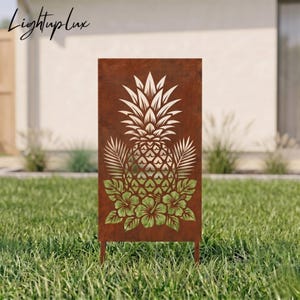 Può includere: Un pannello da giardino rettangolare in metallo con finitura color ruggine, caratterizzato da un design tagliato al laser con un ananas centrale circondato da foglie di palma e fiori di ibisco. Il marchio Lightuplux è visibile in alto a sinistra.