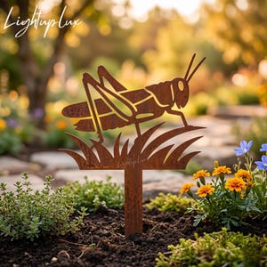 May include: A rust-colored metal garden stake featuring a cutout silhouette of a grasshopper perched on blades of grass. The metal surface has a weathered, oxidized texture. The text Lightuplux is visible on the grass portion of the stake.