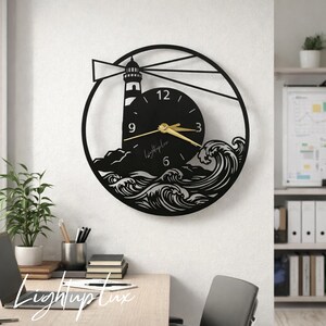 May include: A circular black wall clock featuring a lighthouse silhouette with a beam of light, crashing ocean waves, and a central clock face with gold hands. The clock face displays the numbers 3, 6, 9, 12 and the text LightupLux.