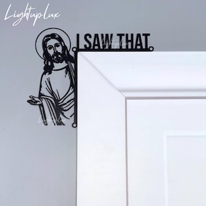May include: Black metal wall decor featuring a silhouette of Jesus peeking around a corner with the text "I SAW THAT."