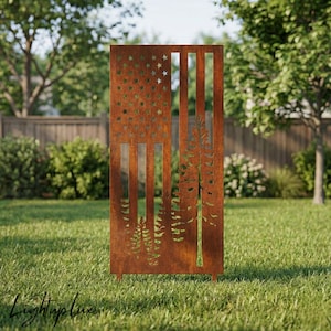 Puede incluir: Una pantalla exterior rectangular de metal marrón oxidado con un diseño de bandera estadounidense recortado. Las estrellas y las rayas están recortadas, y el lado derecho tiene un recorte de pinos. La pantalla está sobre patas cortas en un jardín cubierto de hierba.