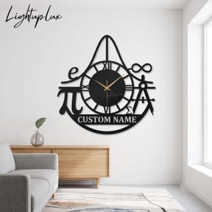 May include: A black wall clock featuring a central circular face with Roman numerals and gold hands. The frame incorporates mathematical symbols including pi, the constant e, an infinity sign, a sigma symbol, and a drafting compass, with the text CUSTOM NAME.