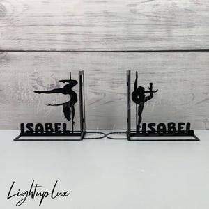 Könnte beinhalten: Schwarze Metall-Buchstützen mit einer Silhouette einer Person, die Pole Dance macht. Die Buchstützen sind mit dem Namen "Isabel" auf jeder Seite personalisiert.