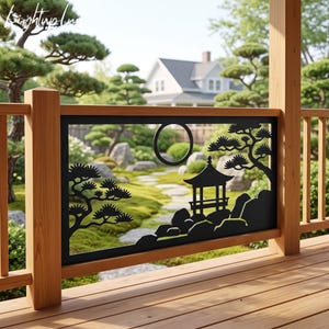 May include: A black metal railing panel featuring a laser-cut design of a pagoda, pine trees, and a circular moon. The rectangular panel is mounted within a wooden frame on a deck, with a blurred garden landscape visible through the cutout design.