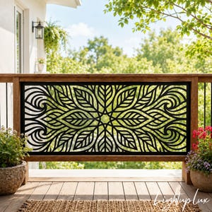 May include: A rectangular black metal privacy screen featuring a laser-cut pattern of symmetrical leaves and swirling lines. The panel is mounted within a wooden frame, creating a decorative barrier with an intricate, repeating botanical design.