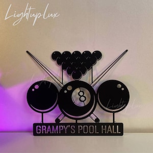 Può includere: Arte da parete in metallo nero con un biliardo con stecche incrociate e un triangolo di palle da biliardo. Il cartello recita "Grampa's Pool Hall".