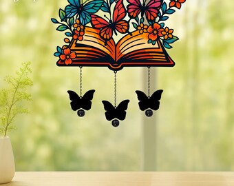 May include: A hanging decorative ornament featuring an open book with orange pages, surrounded by colourful butterflies in shades of blue, red, and orange, with three black butterfly silhouettes suspended by chains below the book.