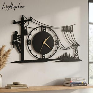 May include: Black metal wall clock featuring a silhouette of an electrician working on a power pole, with power lines, a city skyline, and a clock face. The clock hands are gold. The text "LightupLux" is in the upper left corner.